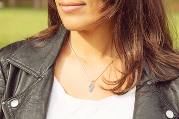 Female neckline wearing tiny silver chain with silver pendant in the shape of hamsa, fatima hand