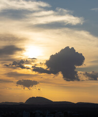 Silhouette of a hill against beautiful golden hour light and beautiful clouds formation and blue shy