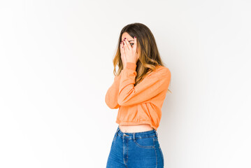 Young caucasian woman isolated on white background blink through fingers frightened and nervous.