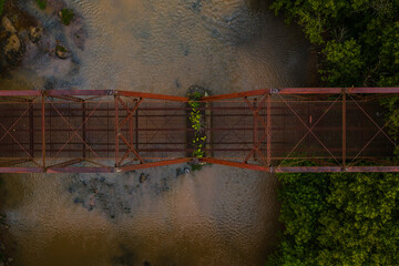 This is an aerial view of the abandoned, rusty Kite truss bridge over a muddy stream in rural West Virginia. - 384196982