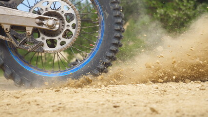 Close up wheel of powerful off-road motorcycle spinning and kicking up dry ground. Professional...