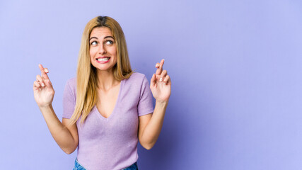 Fototapeta premium Young blonde caucasian woman crossing fingers for having luck