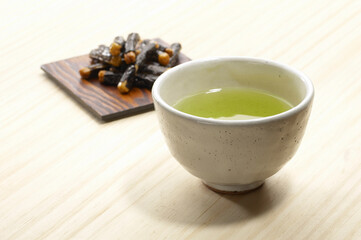 白木のテーブル上のお茶と海苔巻きアラレ