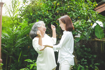 Obraz premium Daughter caring for elderly Asian mother Both of them exercised in the front garden. Make it healthy, strong, a happy family. Senior care concept in retirement age