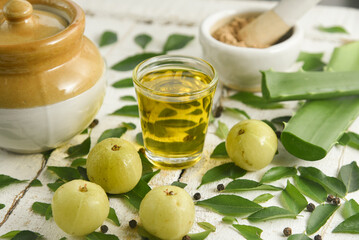 Ayurvedic Oil or Herbal Hair Oil with Herbs tulsi,  curry leaves, oil, amla berry , amla powder , aloe vera ingredients for making medicine Kerala, India. Indian Ayurveda treatment for hair and skin.