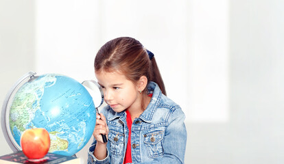 Fototapeta na wymiar Curious little girl looking through magnifying glass on globe