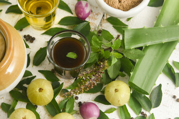 Ayurvedic Oil or Herbal Hair Oil with Herbs tulsi,  curry leaves, oil, amla berry , amla powder , aloe vera ingredients for making medicine Kerala, India. Indian Ayurveda treatment for hair and skin.