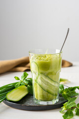 Broccoli and cucumber smoothie, delicious healthy drink made from green vegetables, a glass of smoothies on a white background, garnish of cucumbers and mint