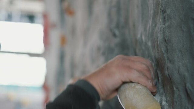 Hand of rock climber close-up, catching on the hook, talc powder flying away.