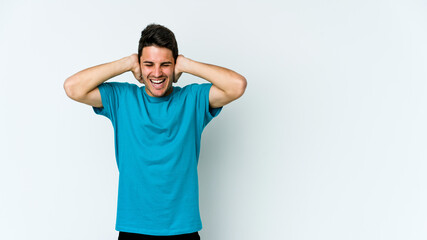 Young caucasian man isolated on white background covering ears with hands trying not to hear too loud sound.