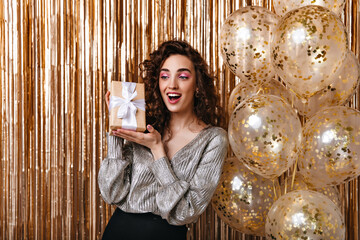 Young girl in silver blouse happily posing with gift box