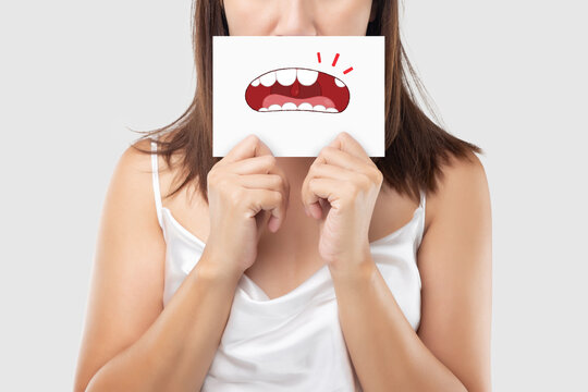 Asian woman in the red shirt holding a brown paper with the broken tooth cartoon picture of his mouth against the gray background, Decayed tooth, The concept with healthcare gums and teeth