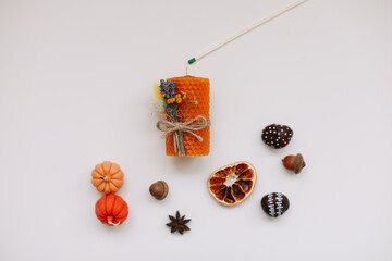 Autumn still life: candles, pumpkin, cinnamon, chestnuts, acorns on white background. Hygge lifestyle, cozy home decor.