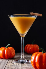 Pumpkin cocktail in glass on wooden table and black background