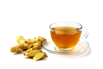 Hot ginger water in a clear glass and fresh ginger on the floor.