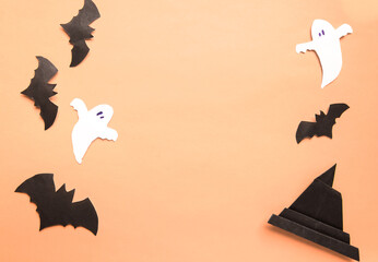 Happy Halloween holiday concept. Halloween decorations, bats, spooky and origami witch hat on beige orange background. Top view.