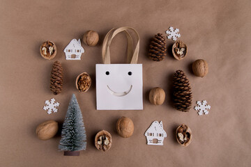 Flat lay on a brown background in the center of a white paper bag, around the figurine decorate for Christmas, nuts, cones, trees, white wooden snowflakes and houses, wooden figurines of Santa and a s