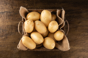 Pile of potatoes in the basket on rustic background. Top view.