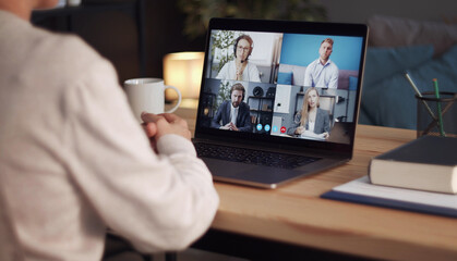 Rear view of person staying home doing online video call using laptop, distant meeting