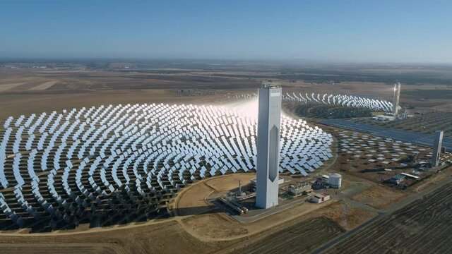 60 fps aerial footage of a сoncentrated solar power station with a hollow tower. Multiple power plants. Solar farm center. Renewable energy concept.