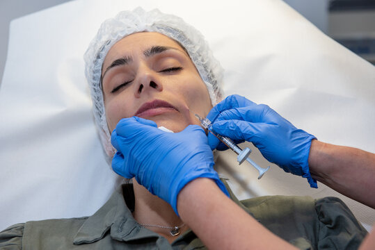 Beautiful, attractive, young woman, lying relaxed in dermatologist ordination, getting a rejuvenating facial treatment with hyaluronic acid filler. Cosmetics and beauty  corrections, skin care concept