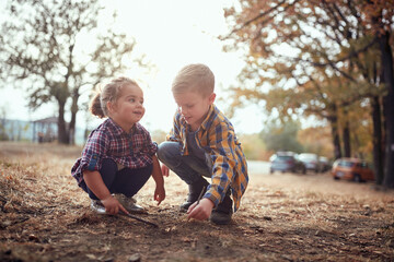Little brother and sister playing on the ground in the forest
