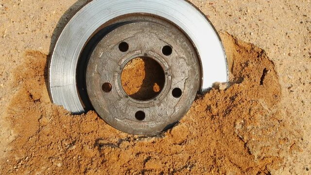 Car brake disc falls from above into a pile of sand. Slow motion, FullHD footage