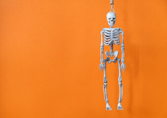 hanged skeleton on an orange background for the holiday halloween