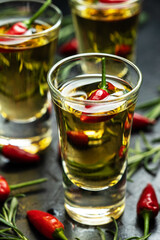 Frozen glass with cold vodka with pepper on dark table