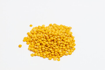 A pile of yellow lentils on a white background