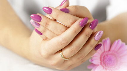 Obraz na płótnie Canvas Elegant hands with fresh lilac pink manicure with daisy gerbera flower
