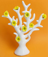 white tree with yellow chrysanthemum flowers on a orange background, creative concept of spring