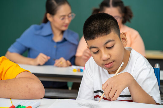 Disability Kid On Wheelchair With Autism Child In Special Classroom