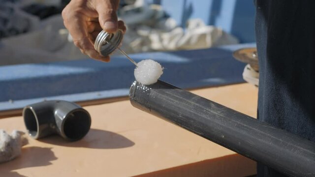 Applying glue to the ends of a plastic pipe. Bonding water pipes between soda. Installation of the pipe bend.