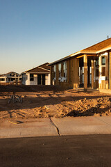 A new house construction that shows the wood frame stands among other new homes in early morning light in Arizona building boom, vertical view.