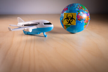 Toy plane next to a globe with the biohazard symbol,symbolizing the global airlines crisis and flights cancellation caused by the coronavirus and COVID-19