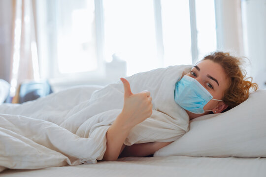 Woman lying in bed with surgical mask, coronavirus protection