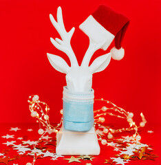 white deer in protective face mask on red background, minimal creative concept of Christmas and New Year