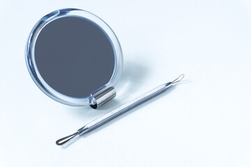 Small mirror and cosmetic tool for removing acne on white background. Problem skin, cleaning skin concept.