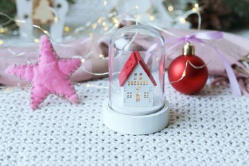 Merry Christmas, toy house, New Year decorations, illumination, spruce branches on the background of a knitted plaid, the concept of home comfort, congratulations on the winter holidays  