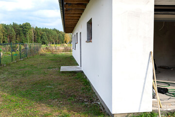 A newly applied layer of white silicone plaster on the wall of the house, the window and door are...