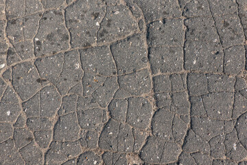 Fragment of the old asphalt road surface. There are cracks and small stones. Background. Texture.