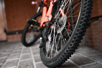 orange bike parked by red brick wall. bottom view of a bicycle wheel