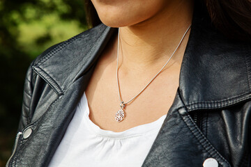 Female neckline wearing tiny silver chain with silver pendant in the shape of lotus