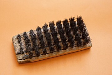 one old gray wooden clothing brush with black plastic bristles on a brown table