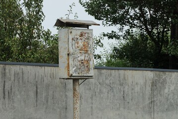 one old gray metal box for electrical wires outside by a concrete wall