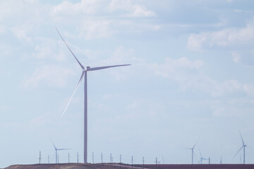 Fototapeta premium Wind generators farm sustainable industry. Cloudy blue sky cloudscape with Energy turbines power