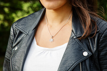 Female neckline wearing tiny silver chain with silver pendant in the shape of lotus