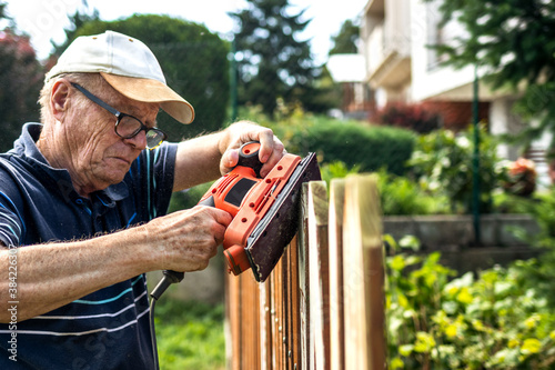 Senior Man Sanding Wooden Fence 