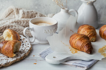 Delicious breakfast with fresh croissants and cup of coffee on a white wooden background. Delicious Baking